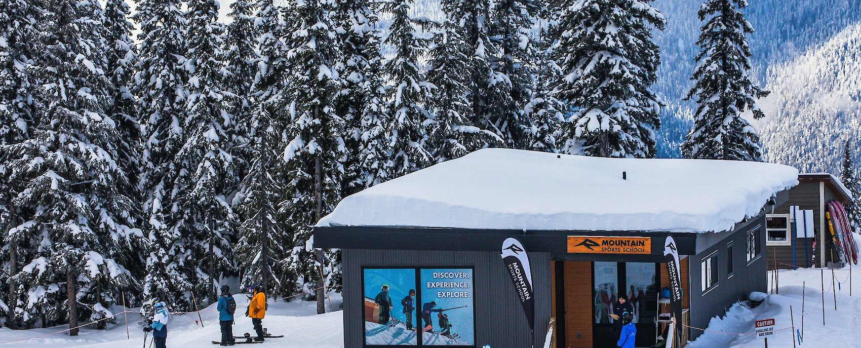 Skiers and snowboarders prepare for lessons in a scenic mountain resort with snow and clear skies