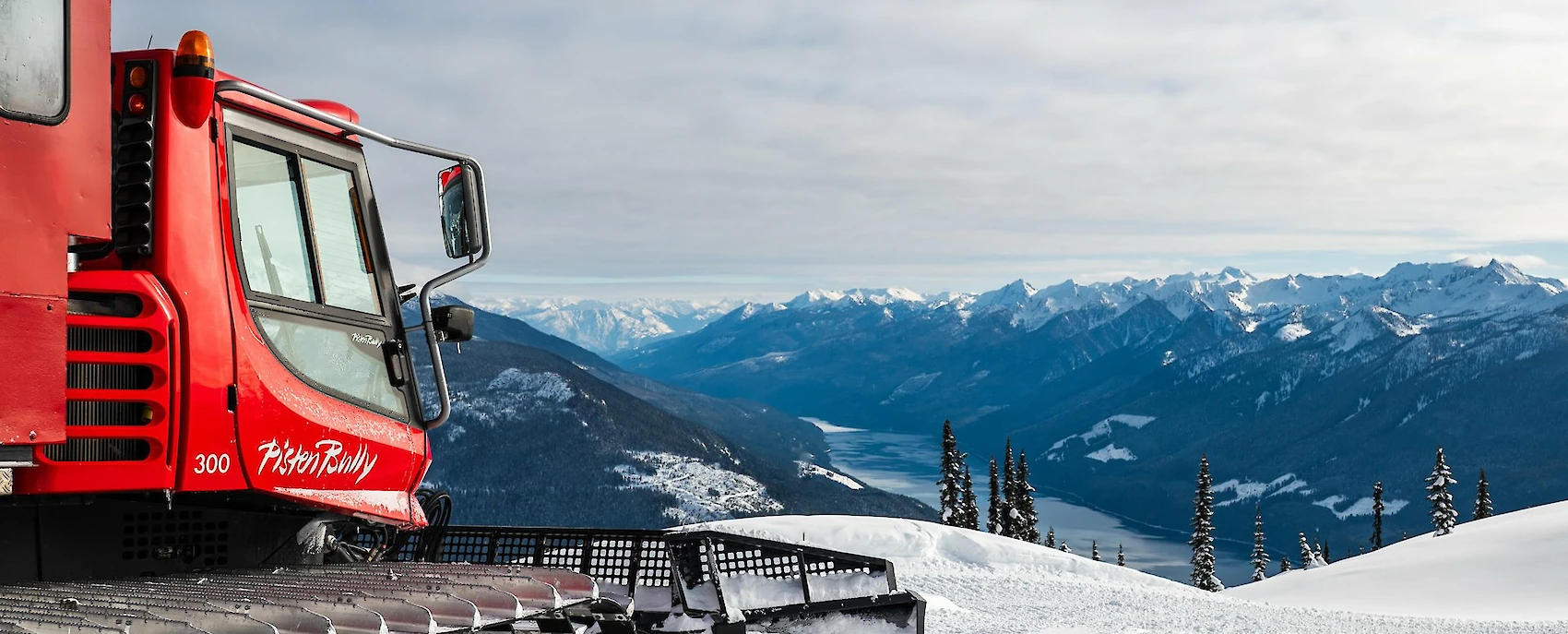 Cat preparing the terrain for an exhilarating cat skiing experience, offering stunning views of snow-covered peaks and valleys in a winter paradise