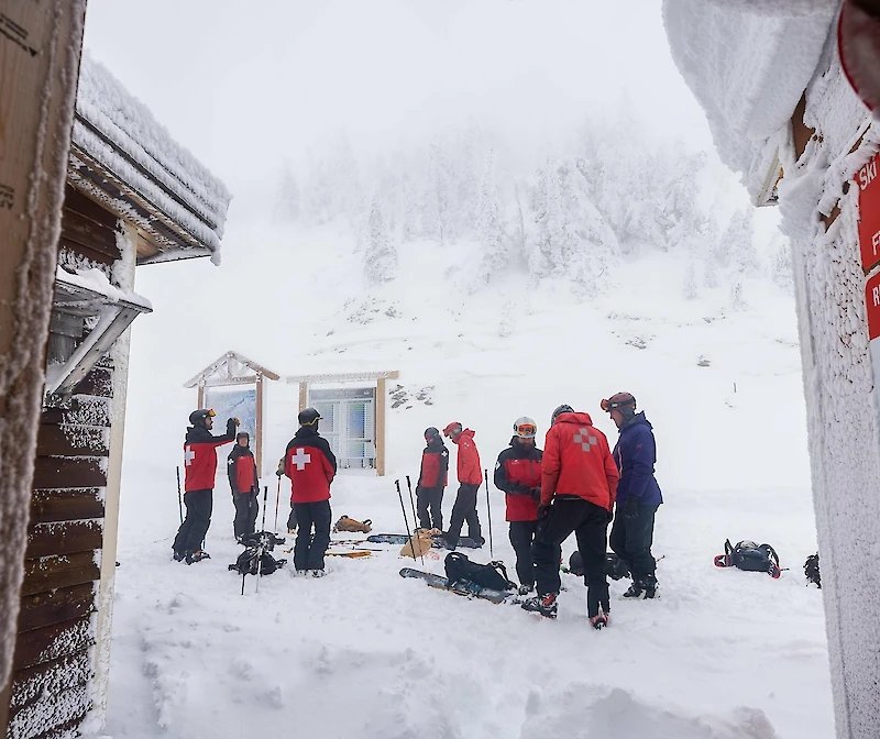 Ski patrol team preparing for winter in deep snow at a first aid station